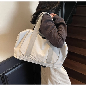 Gros plan du sac de voyage beige grande capacité avec logo Welaibag porté par un modèle