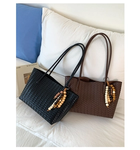 Detail of woven tote bags in black and brown with bohemian beaded charms and long straps