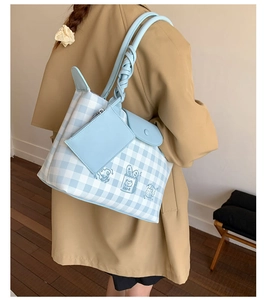 Detail of blue plaid tote bag with cartoon illustration and twisted knot leather strap