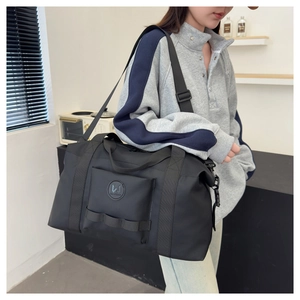 Man wearing a large black nylon travel bag showing the capacity and adjustable strap