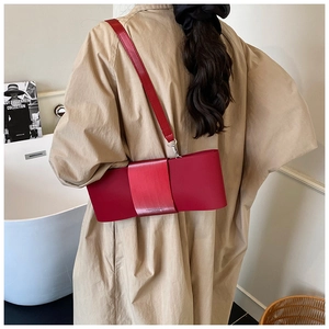 Detail of red bow-shaped leather shoulder bag with fine strap and printed logo lettering