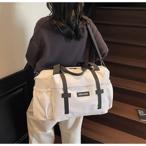 Détail d'un grand sac de voyage ivoire montrant la poche à boucle et le filet latéral