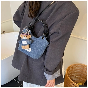Détail du sac seau en denim avec breloque ours et poignée noire brillante