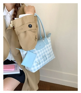 Detail of blue gingham tote bag featuring cartoon cat print and matching mini pouch