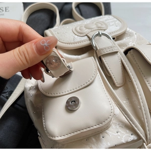 Detail of magnetic snap closure and 3D bow on beige jacquard mini backpack