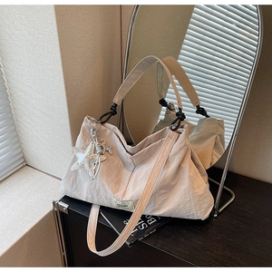 Detail of beige nylon tote bag with pleated texture and a large silver sequin star charm