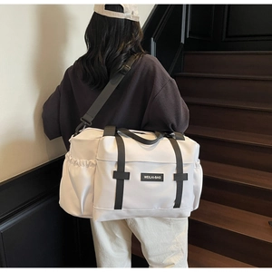 Détail du grand sac de voyage blanc avec bandoulière réglable et poignées noires solides