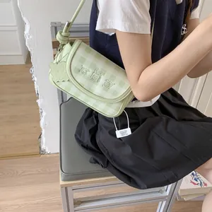 Close-up of green checkerboard crossbody bag with animal embroidery and star charm