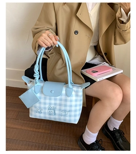 Detailed embroidery of a cartoon cake on a light blue checkered tote bag with mini pouch