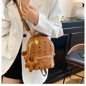Detailed view of brown mini backpack featuring teddy bear pattern and hanging charm