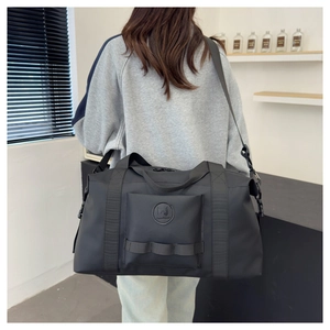 Detail of a large black travel bag with matte waterproof fabric and adjustable strap
