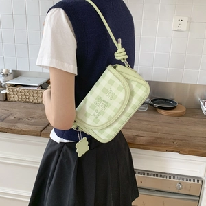 Detail of green plaid shoulder bag with cute cartoon prints and flower charm