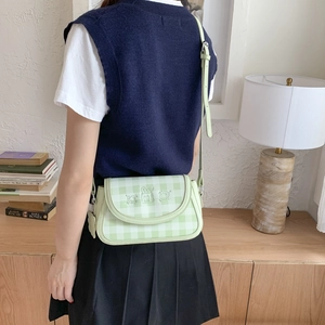 Detail of light green checkered crossbody bag with cute 3D cartoon animal character charms