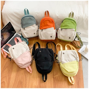 Mini multi-color canvas backpacks displayed in a neat row on a warm wooden floor