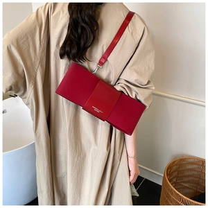Model showing red bow-shaped leather crossbody bag with FASHION & BAGS logo detail
