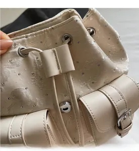 Close-up of cream drawstring backpack with jacquard fabric, rhinestones and silver metal hardware
