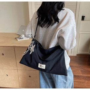 Rear view of a black large-capacity canvas tote bag with a star charm on a casual model