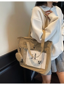 Khaki nylon tote bag with transparent window and coin purse on model's shoulder