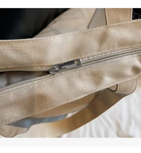 Detailed macro view of the smooth metal zipper and beige canvas fabric texture