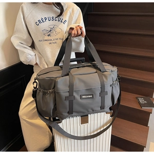 Sac de voyage gris fixé à la poignée d'une valise pour un transport facile