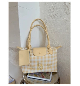 Detail of yellow checkered canvas tote bag with embroidered cake icons and matching coin purse