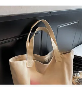 Detail of beige canvas tote bag showing handle quality and red BALIMAN lettering print