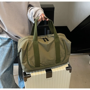 Détail du sac de voyage vert olive montrant les poignées renforcées et la double fermeture