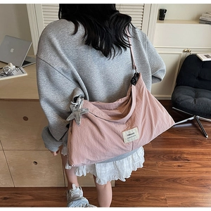 Detail of light pink crossbody bag with Swagger label and silver star charm accessory