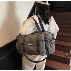 Sac de voyage gris spacieux sur escalier avec nylon résistant et bandoulière réglable