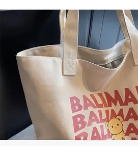 Close-up of durable beige canvas tote bag with BALIMAI red letters and bear print