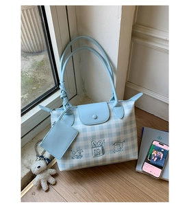 Close-up of blue plaid tote bag with cat embroidery, coin purse, and plush bear charm