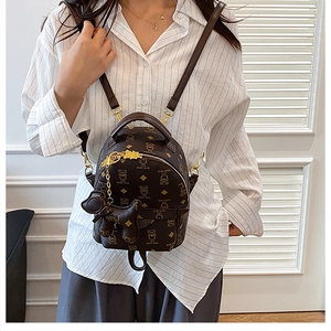 Mini brown teddy bear backpack detail showing the leather dog charm and thin straps