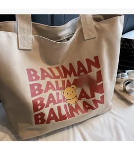 Detailed macro of a canvas tote bag featuring red Baliman text and a cute brown bear graphic