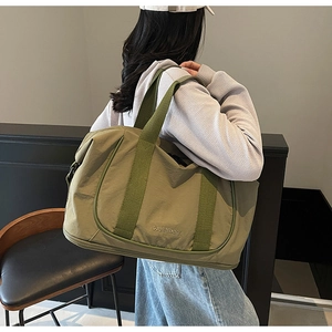 Gros plan du sac de voyage vert olive avec bandoulière et logo sur l'épaule