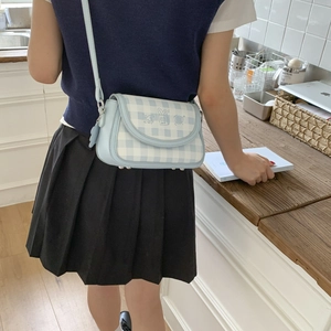 Detailed view of a light blue plaid crossbody bag featuring cute cartoon illustrations