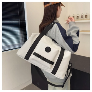 Large white travel tote bag with black nylon straps worn by a model in a minimal setting