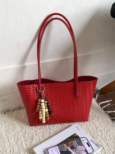 Large capacity red woven tote bag for women with tassel wooden beads on neutral background