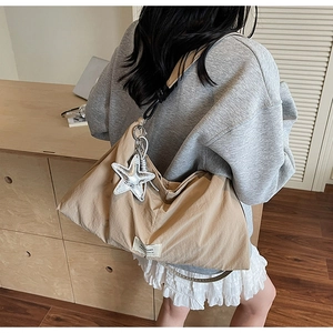 Detail of light khaki nylon tote bag featuring black strap and silver star charm accessory