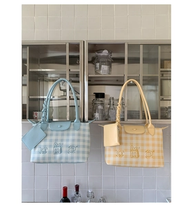 Detail showing checkered tote bag with woven handles and a cute cartoon cat illustration