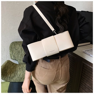 Close-up of creamy white leather bow-shaped shoulder bag with stylish strap detail