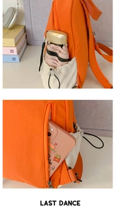 Detail of orange backpack with functional drawstring side pocket and anti-theft back pocket