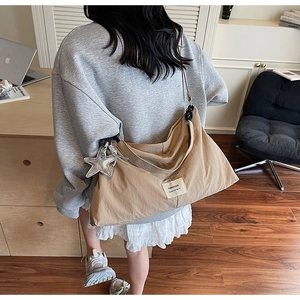 Khaki canvas crossbody tote bag with star charm shown in a casual lifestyle setting