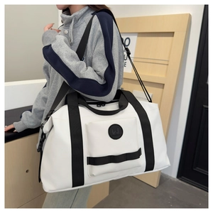 Detail of white travel bag showing the spacious front zip pocket and sturdy black handles