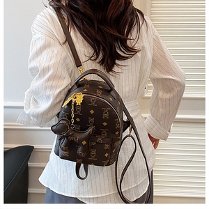 Detail of dark brown mini backpack with Teddy Bear print and dog charm accessory