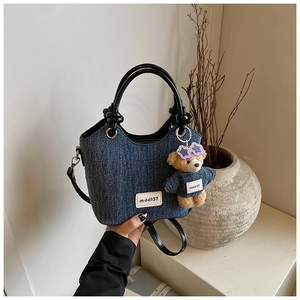 Détail d'un sac seau en jean avec pendentif ours en peluche et anses noires