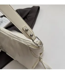 Close-up of cream leather shoulder bag showing silver D-ring and rivet metal hardware