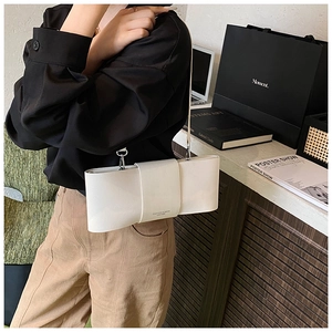 Detail of a creamy white leather shoulder bag featuring a stylish oversized bow design