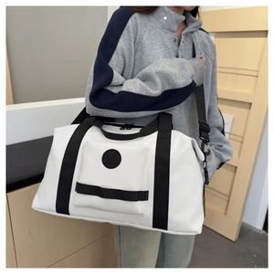 Detail of a large white travel duffel with black straps and round logo on leather texture