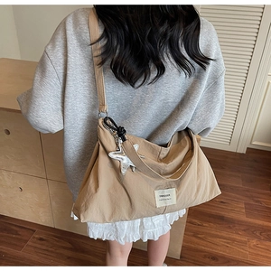 Rear view of khaki nylon canvas crossbody bag with silver star charm and label