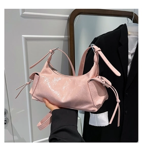 Dettaglio borsa rosa lucida con tracolla regolabile e design con tasca laterale